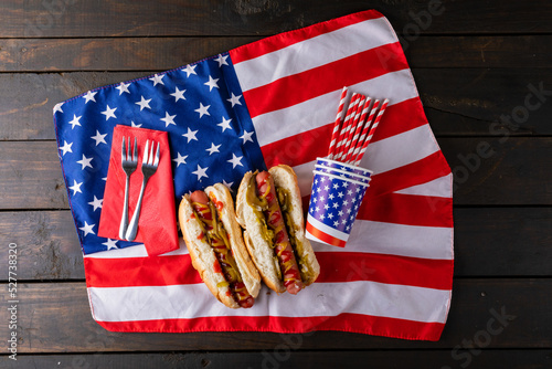 Hot dogs with jalapenos served on american flag with fork, straw and disposable cups at table