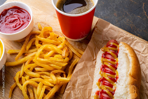 Close-up of hot dog meal with drink on serving board at table