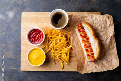 Overhead view of hot dog meal served on serving board at table
