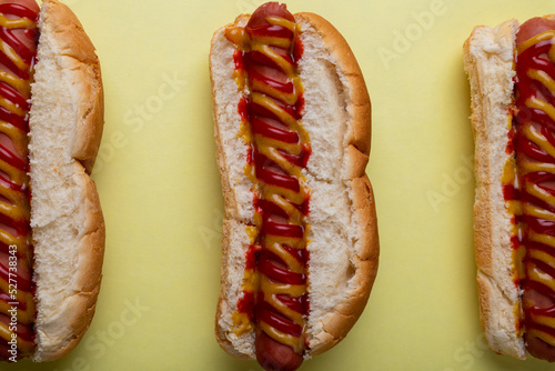 Directly above close-up shot of sauces on hot dogs arranged side by side on yellow background