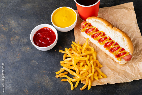 High angle view of sauces by french fries, hot dog and drink on brown wax paper at table