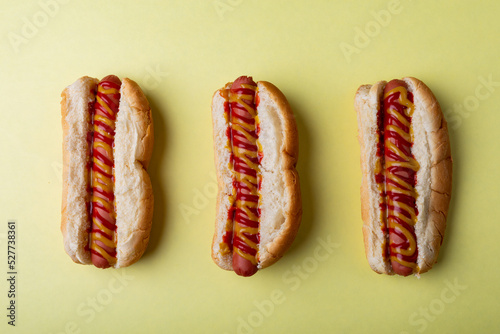 Directly above shot of sauces on hot dogs arranged side by side on green background
