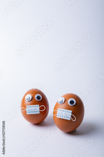 Doodle eyes and mask on easter eggs over white background with copy space