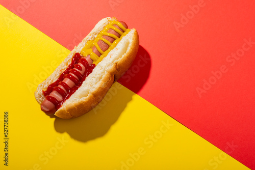 High angle view of hot dog with mustered and tomato sauce on two tone background with copy space