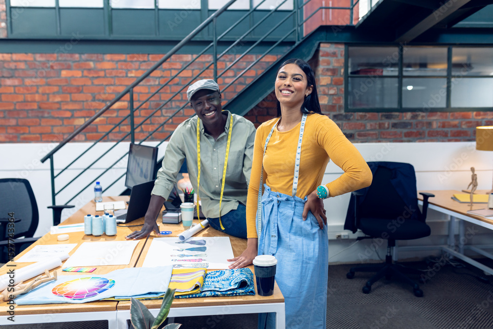 Portrait of smiling multiracial male and female fashion designers working at desk Portrait of smiling multiracial male and female fashion designers working at desk