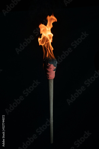 ancient wooden torch isolated on black background photo