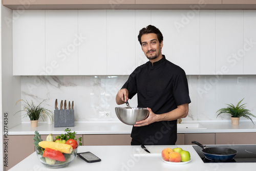 Young handsome male chef in cooking in the kitchen