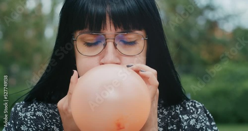 a happy woman inflates balloons and they burst, showing that everything is wrong with condoms and they are torn.