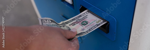 Photography Woman inserting dollar bills into ATM on street closeup