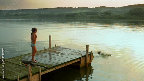 Child running and jumping off pier in sea water. Slow motion. Boy having fun in summer vacation. Happy lifestyle concept. High quality FullHD footage