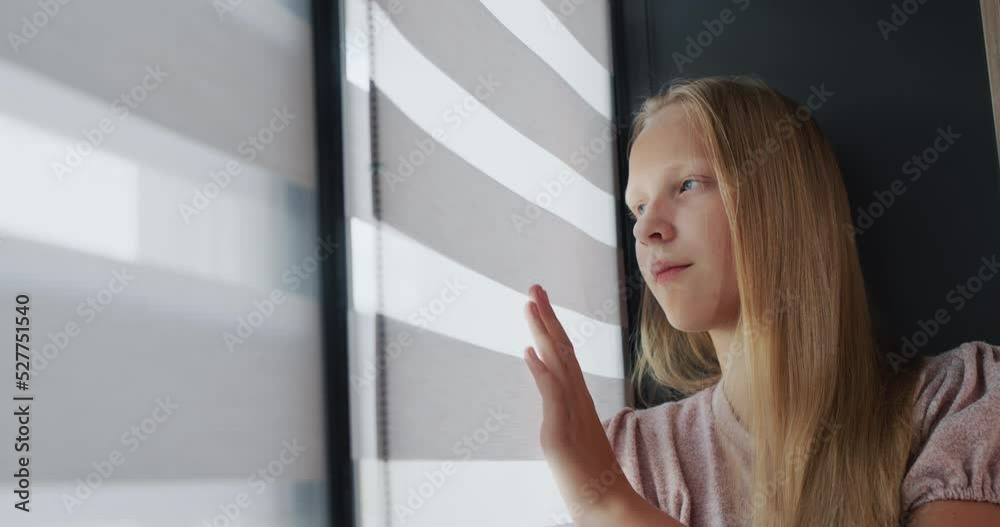 Teenage girl sitting on the windowsill, looking out the window Teenage girl sitting on the windowsill, looking out the window
