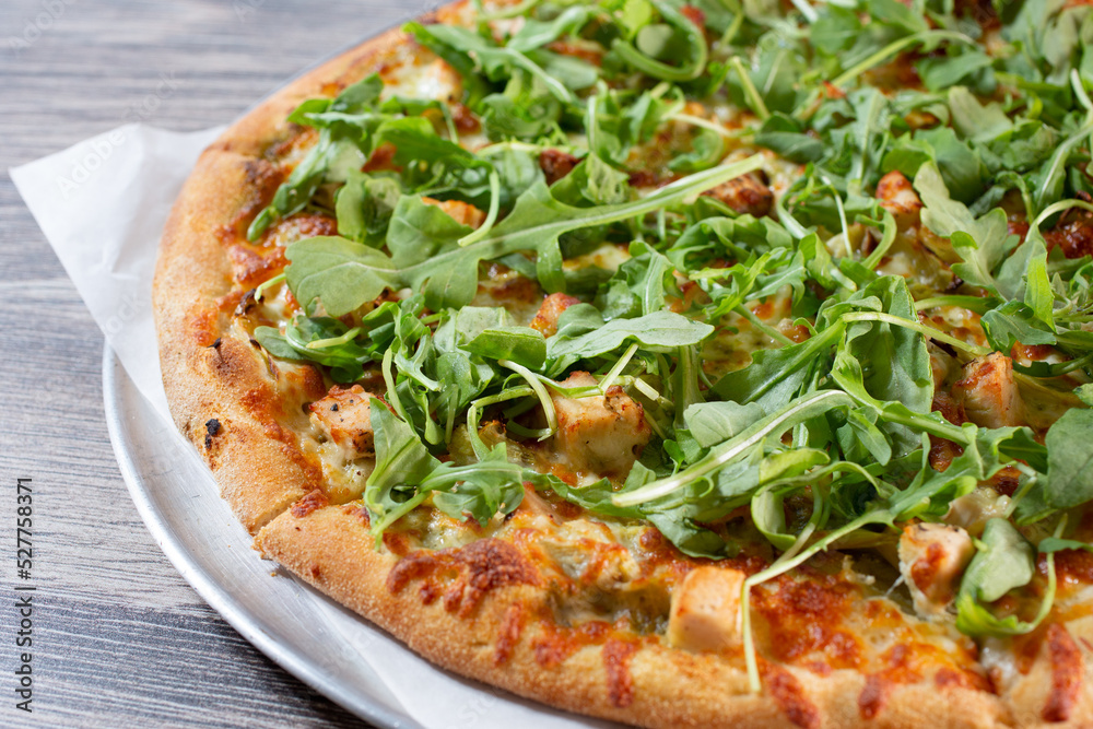 A view of a chicken and arugula pizza. A view of a chicken and arugula pizza.
