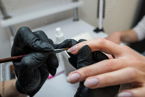 The manicurist covers the client s nails with red varnish. Manicure in a beauty salon.