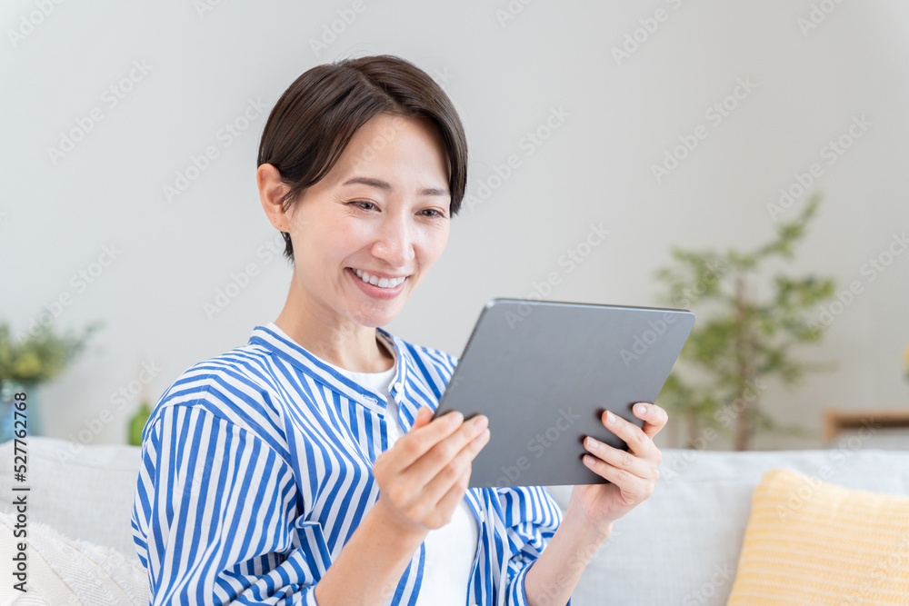 家でタブレットを見る女性 家でタブレットを見る女性