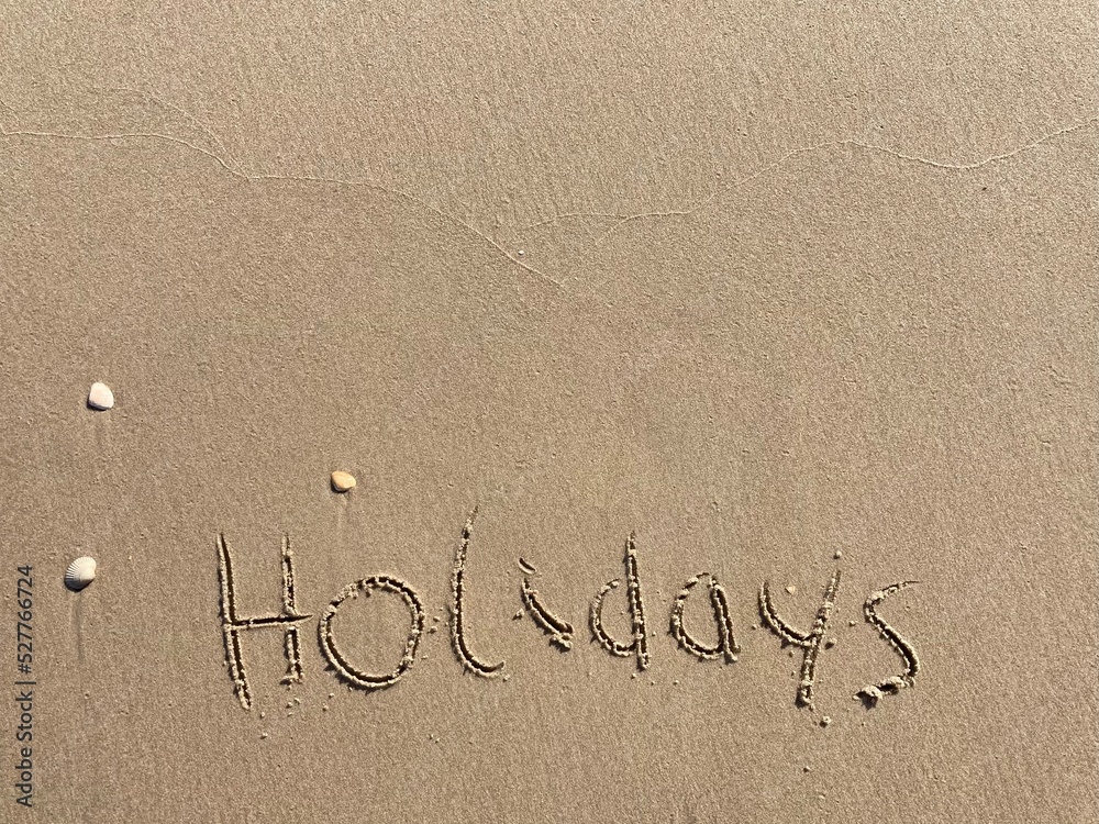 on the beach is carved with letters in the smooth sand the writing holidays