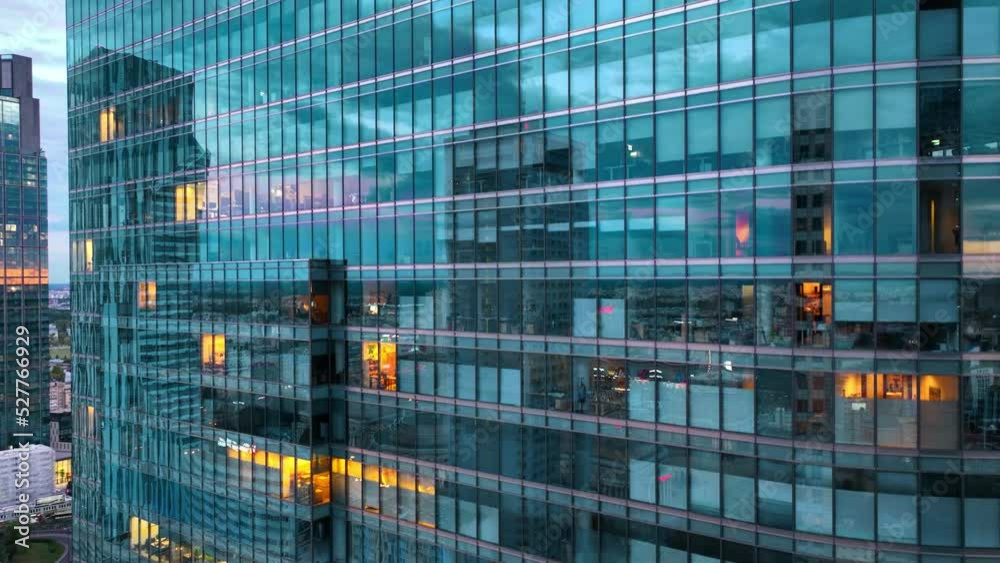 Aerial view of office windows in a modern glass skyscraper at night. Close-up of windows of offices in a skyscraper, business centre in a big city.