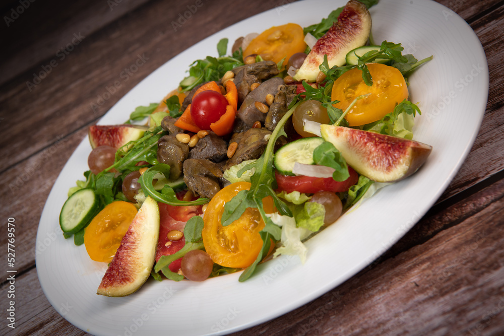 Recipe for fried chicken liver and gizzards with salad and tomatoes, cucumber, figs, grapes on a white plate, High quality photo