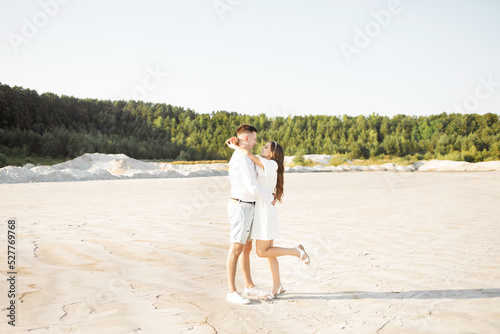 Young couple hugging on a sandy beach on a sunny day © Yuliia