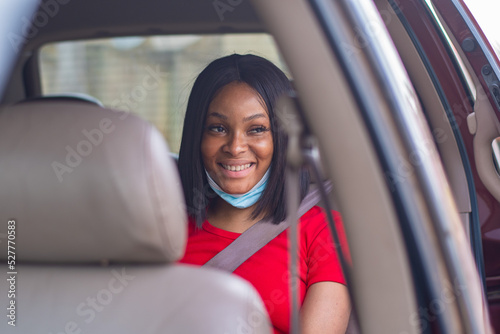 pretty african lady with a face mask commuting in a taxi smiling