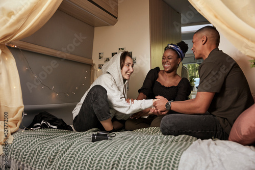 Smiling friends sitting on bed in camper van photo