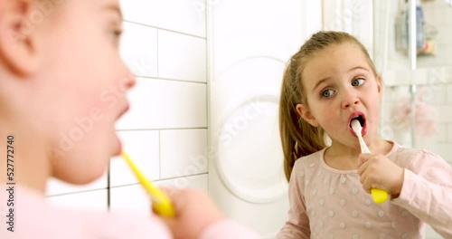 Little girl brushing her teeth with a toothbrush in bathroom in the morning