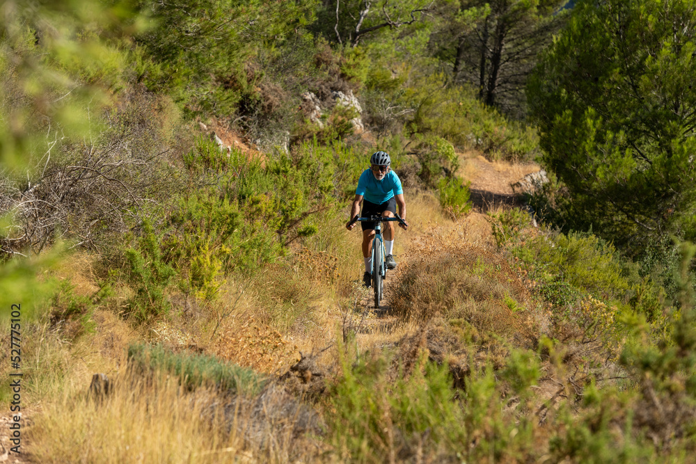 A male cyclist in a mediterranean forest gravel road bicycle ride in the Costa Blanca, Alicante, Spain