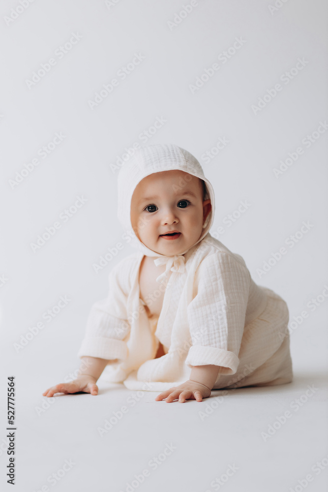 Cute studio portrait of a little newborn girl posing for a photo on a light background. A baby who has already learned to crawl and sit Cute studio portrait of a little newborn girl posing for a photo on a light background. A baby who has already learned to crawl and sit