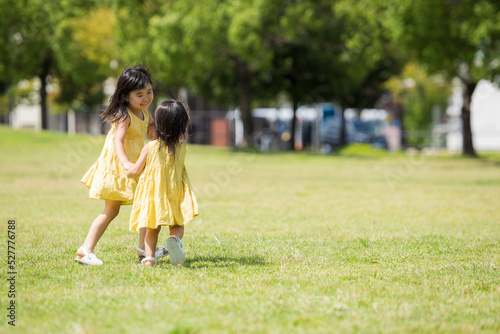 夏の芝生の公園で元気に遊ぶ姉妹