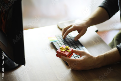 A man with a gift in his hand sits in front of the monitor screen. Order a gift for home and office.