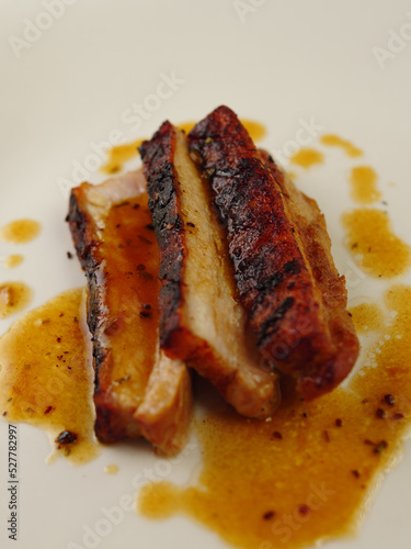 Crispy Pork Belly on a White Plate With Juices