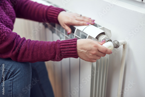 Woman heating on a chilly winter day, energy and gas crisis, cold room, heating problems.