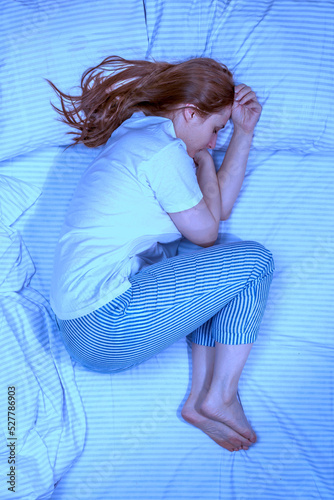 Woman sleeping in bed at home. Deep restful sleep. Lady with long brown hair wearing a nightgown. High Angle View girl lying in a nightie on clean white bed linen with cozy blanket photo