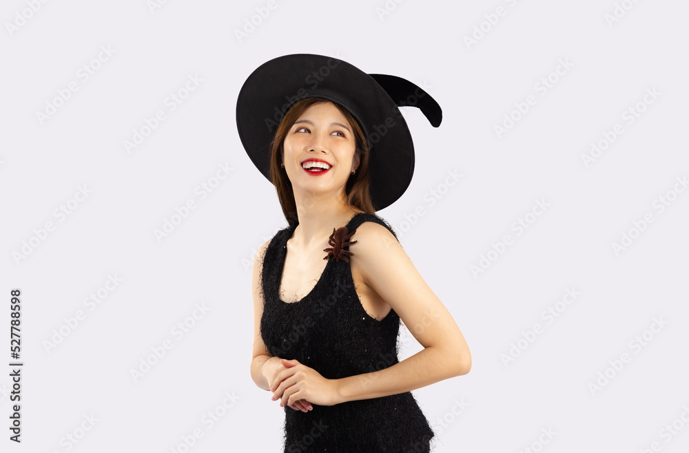 Young asian girl in black dress wearing witch hat to celebrate halloween posing on white background. Young asian girl in black dress wearing witch hat to celebrate halloween posing on white background.