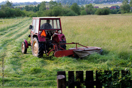 Old red tractor  cutting up hay in a field