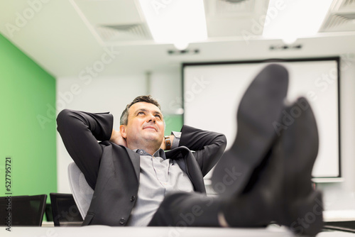 Happy relaxed businessman with feet on the desk in office
