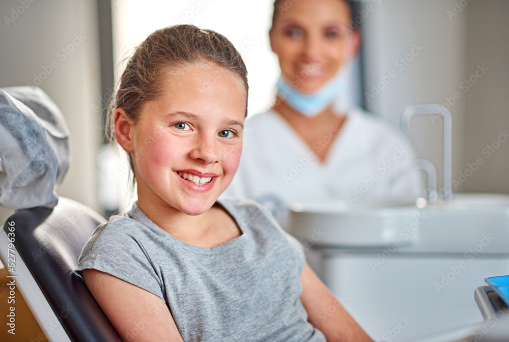 Shes in for a routine check-up. Shot of a young girl sitting in a dental chair with her dentist in the background. Shes in for a routine check-up. Shot of a young girl sitting in a dental chair with her dentist in the background.