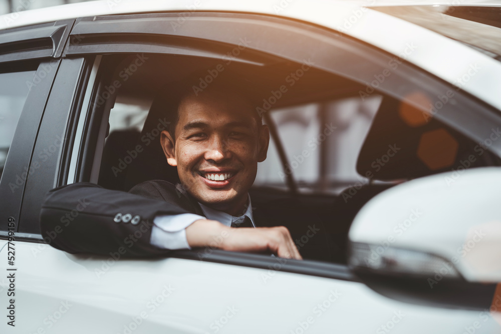 Happy young Asian businessman driving a car.