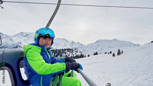 Portrait of a boy with ski going up on chairlift at mountains