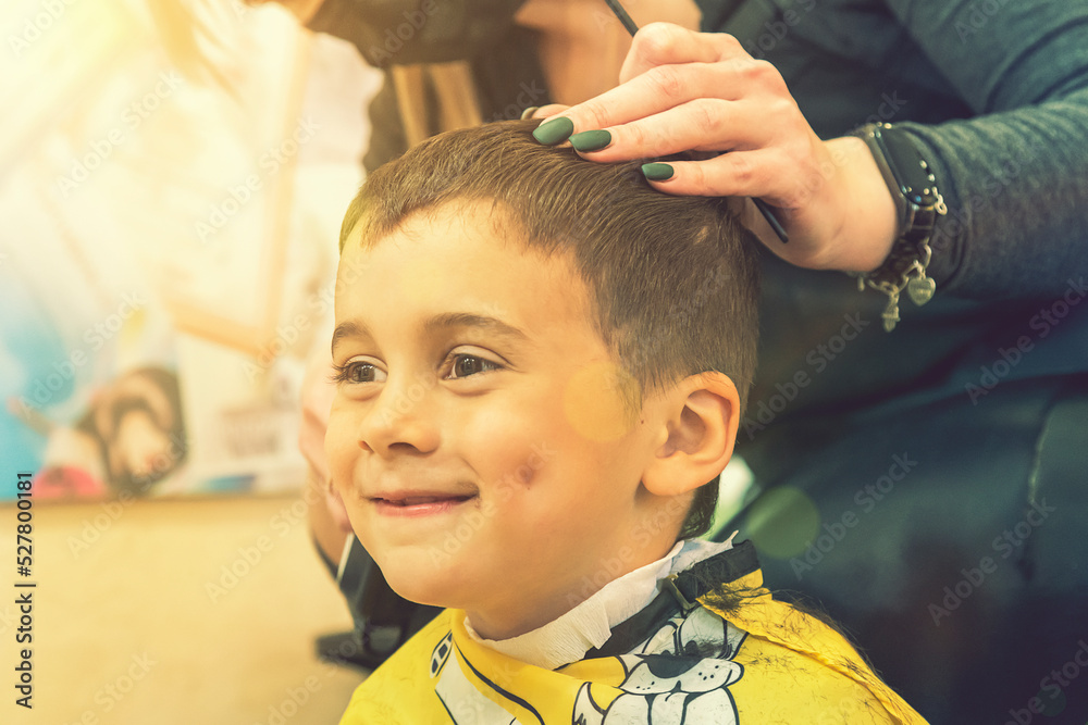 little boy having a haircut at hair salon..Children hairdresser with scissors and comb is cutting little boy. Contented cute preschooler boy getting the haircut. toned little boy having a haircut at hair salon..Children hairdresser with scissors and comb is cutting little boy. Contented cute preschooler boy getting the haircut. toned
