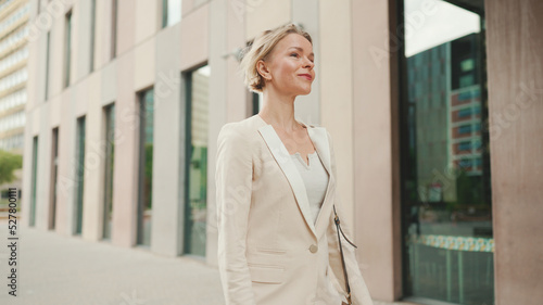 Businesswoman in beige suit walks outside past business building Free Download Businesswoman in beige suit walks outside past business building - GFXLoad