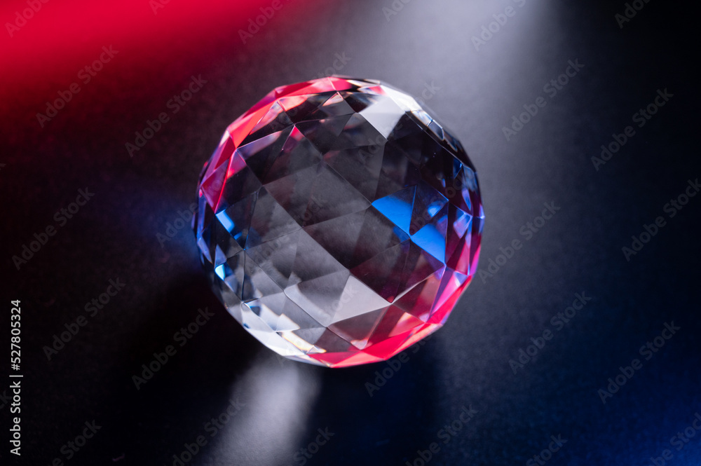 a crystal faceted ball shimmers with blue-red highlights on a dark background. a crystal faceted ball shimmers with blue-red highlights on a dark background.