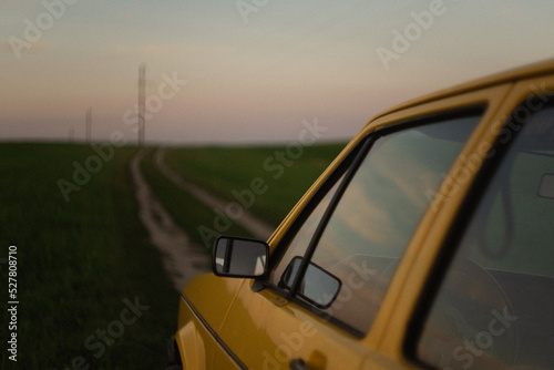 Yellow retro car on the countryside road at sunset. 