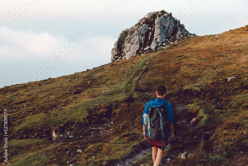 Tourist with backpack walking up on hill