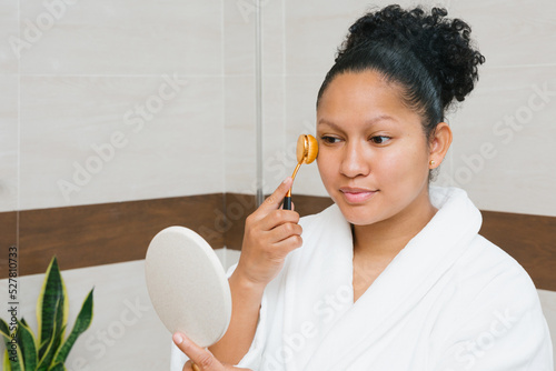 Content ethnic woman applying foundation on face photo