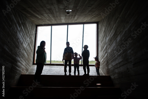 Mother with children stand against large panoramic windows at cube room.