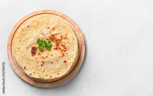 Chapati, traditional Indian flatbreads with fresh parsley on a gray background. Top view, horizontal