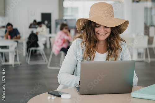 Woman smiling and using laptop in airport terminal