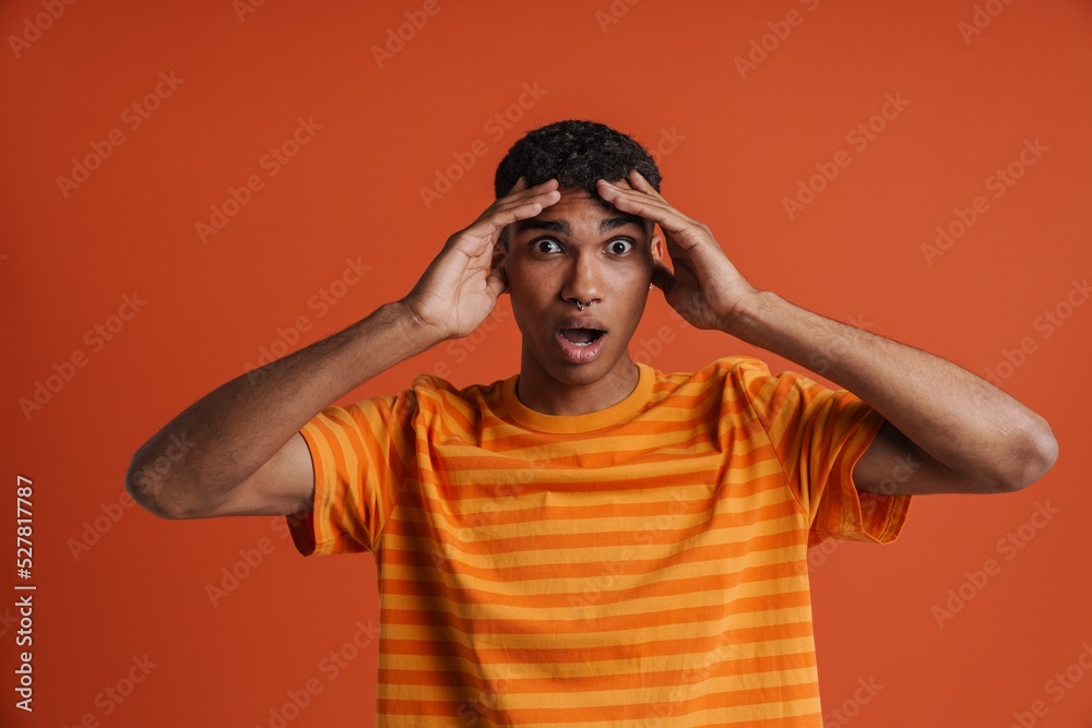 Young handsome shocked african man with piercing holding his head
