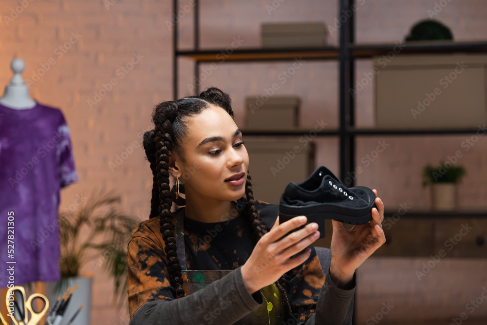 Smiling african american designer holding shoe in workshop. Smiling african american designer holding shoe in workshop.