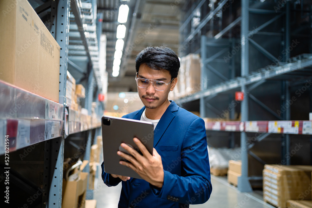 Asian male businessman in a large warehouse . Happy workers in distribution center Concept of supply chain technology and logistics network. Logistics and export business. Factory warehouse. Asian male businessman in a large warehouse . Happy workers in distribution center Concept of supply chain technology and logistics network. Logistics and export business. Factory warehouse.